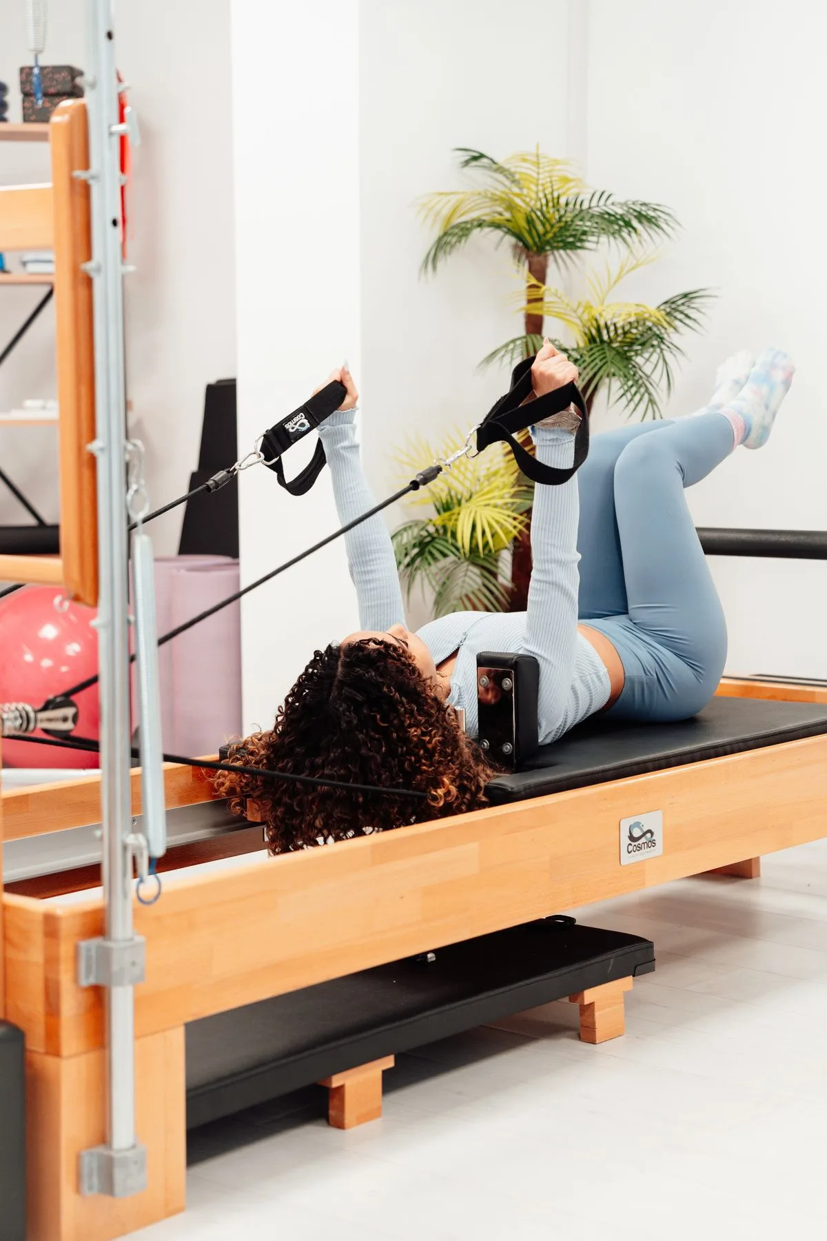 Woman performing controlled movement on a Pilates reformer