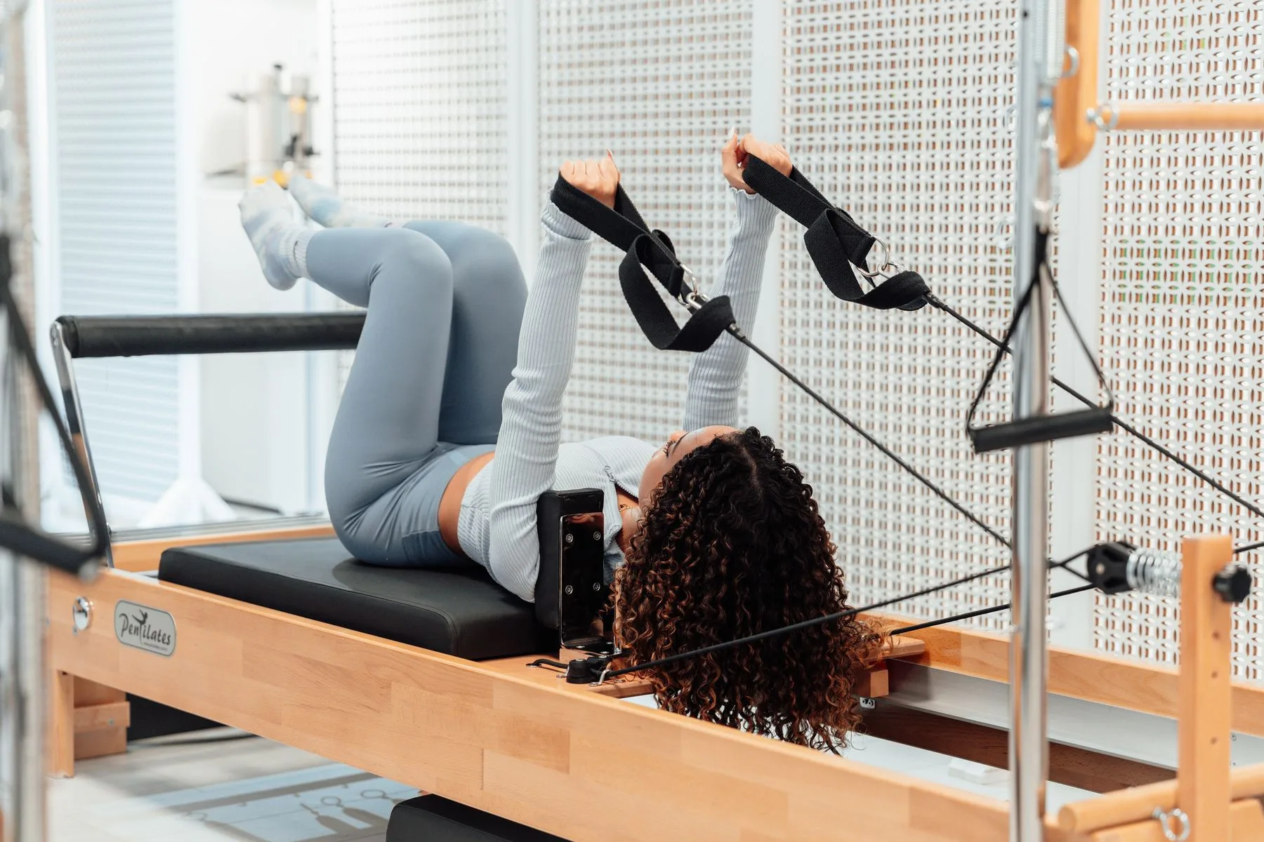 Woman performing an exercise on a Reformer Pilates machine